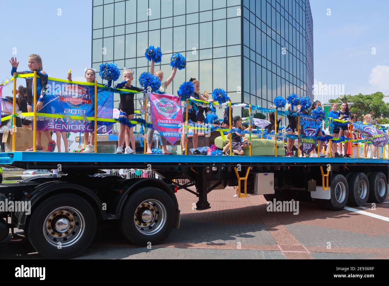 Young cheerleaders riding in the back of a truck and waving their pompoms at a Christmas parade in Tauranga, New Zealand Stock Photo