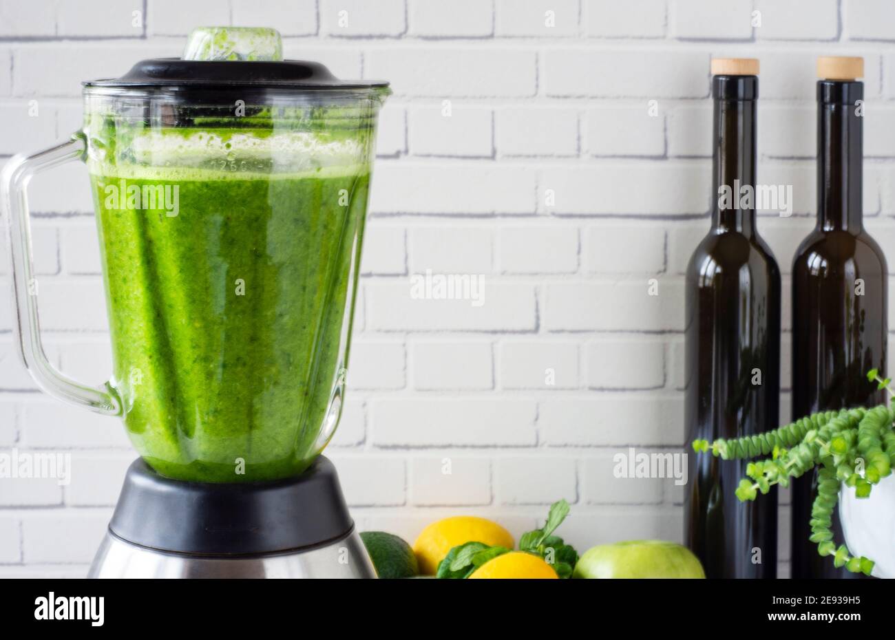 In front of the wall, green fruits and vegetables and a healthy drink