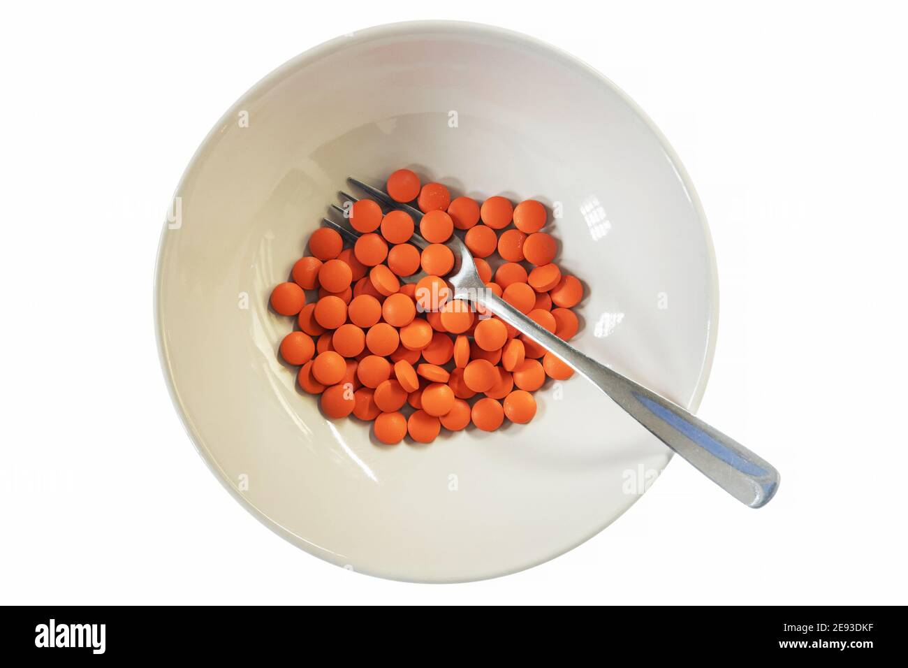 A bowl of orange pills with a fork Stock Photo
