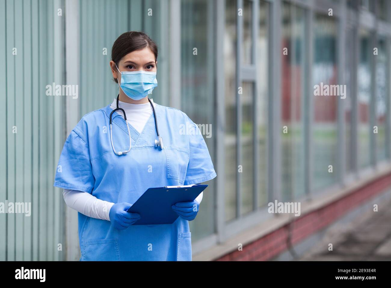 Portrait of tired exhausted female caucasian NHS key doctor in front of clinic or hospital,Coronavirus patient triage for COVID-19 virus disease,globa Stock Photo