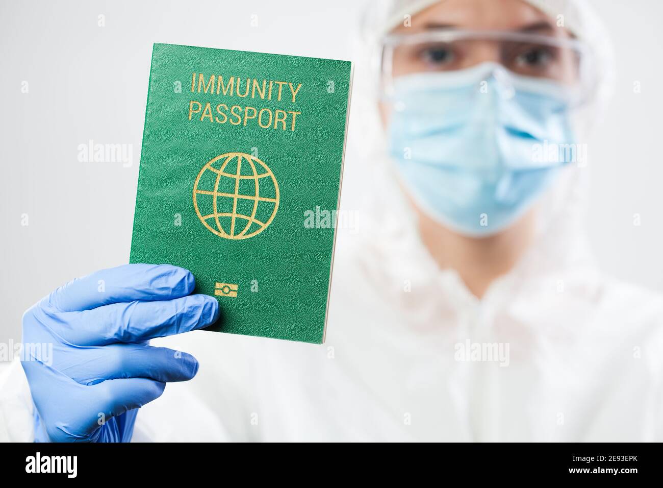 Medical US healthcare security officer worker in personal protective equipment holding green immunity passport ID card,risk free certificate document Stock Photo