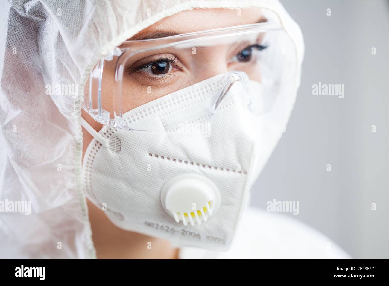 Closeup of tired female doctor,nurse or lab tech wearing PPE protective suit,white face mask and goggles,lost hope due to many patient deaths,looking Stock Photo