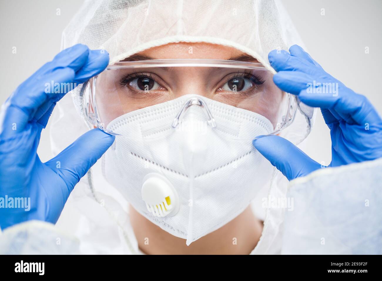 Female NHS doctor,nurse or lab tech virology scientist in PPE,putting on protective  eyewear goggles,wearing blue latex gloves and white face mask,clos Stock  Photo - Alamy