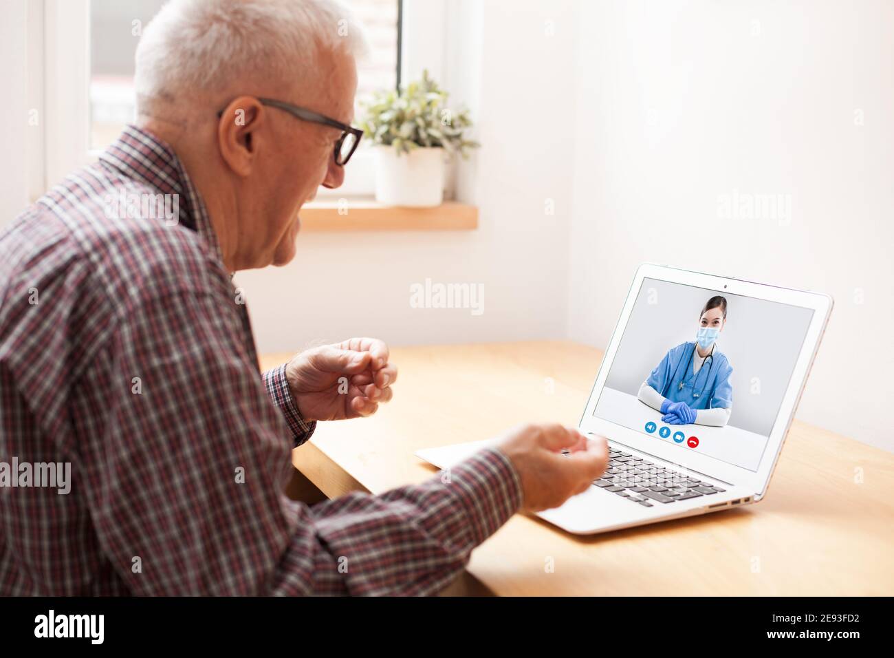 Elderly caucasian retired man talking to young UK female doctor via online video call,medical worker seeing patient in virtual house call,telemedicine Stock Photo