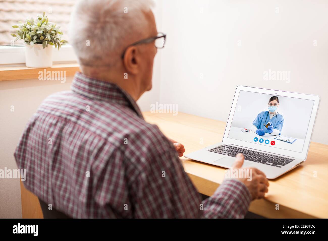 Young female UK e-doctor consulting elderly man,online video help line virtual medical appointment,GP prescribing medication to senior patient,telemed Stock Photo