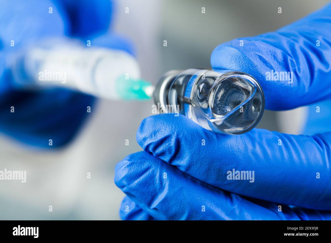 COVID-19 UK vaccine clinical trial concept,hands in blue gloves holding bottle vial,potential therapy cure for Coronavirus patients,immunization again Stock Photo