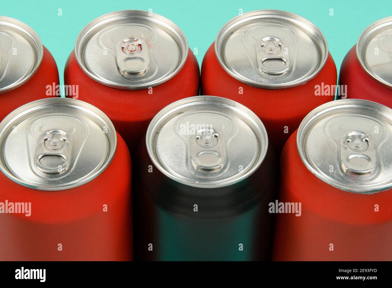 red soda cans lined up seen from above with a mixed black can Stock