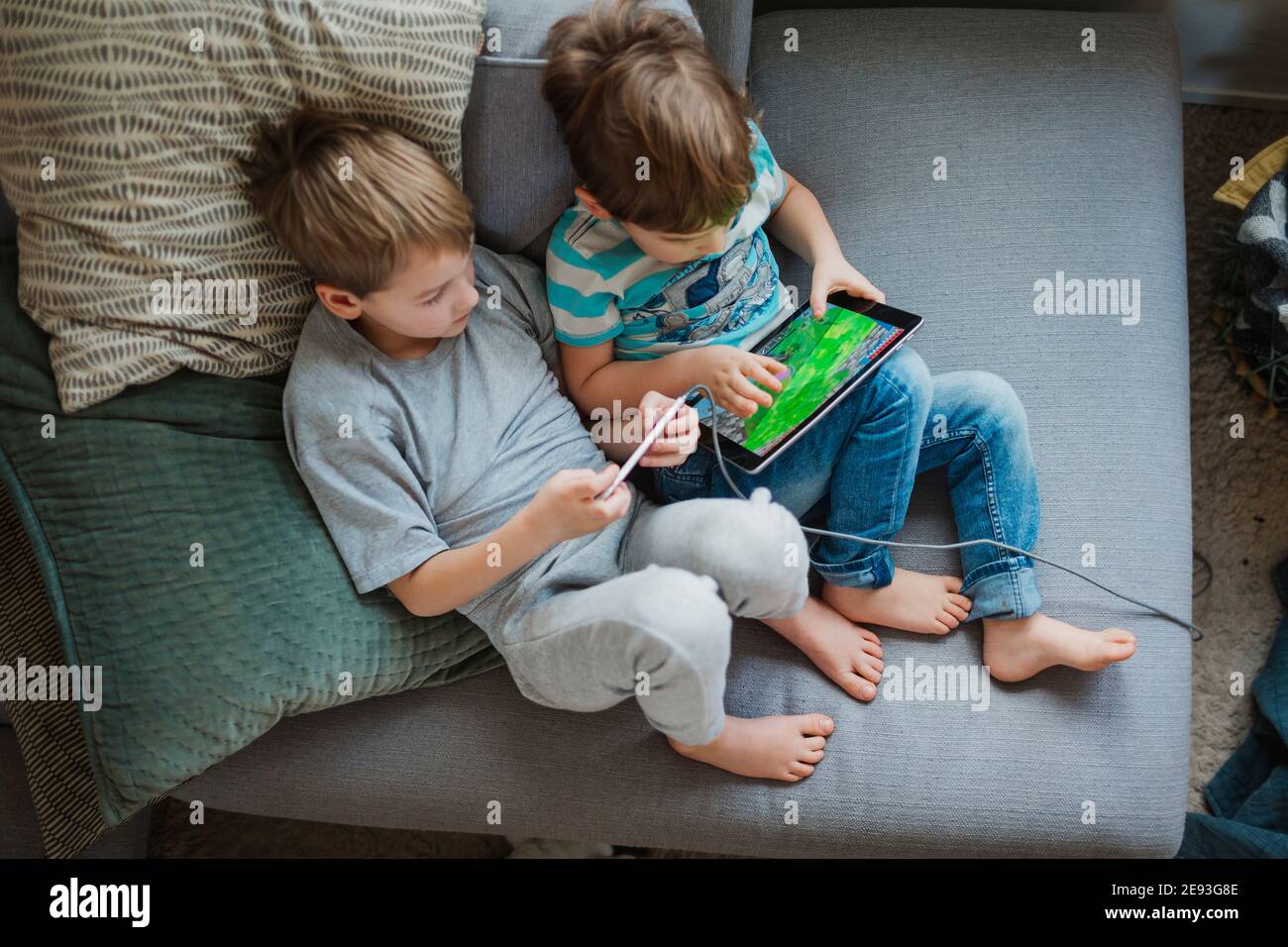 Boys using digital tablet on sofa Stock Photo