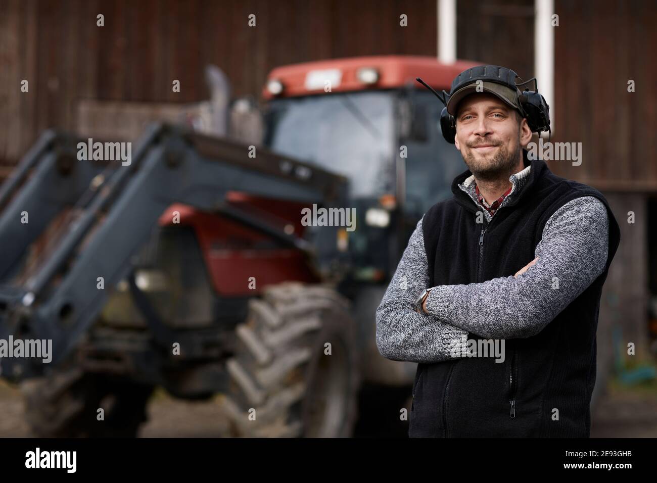 Farmer standing next to tractor Stock Photo - Alamy