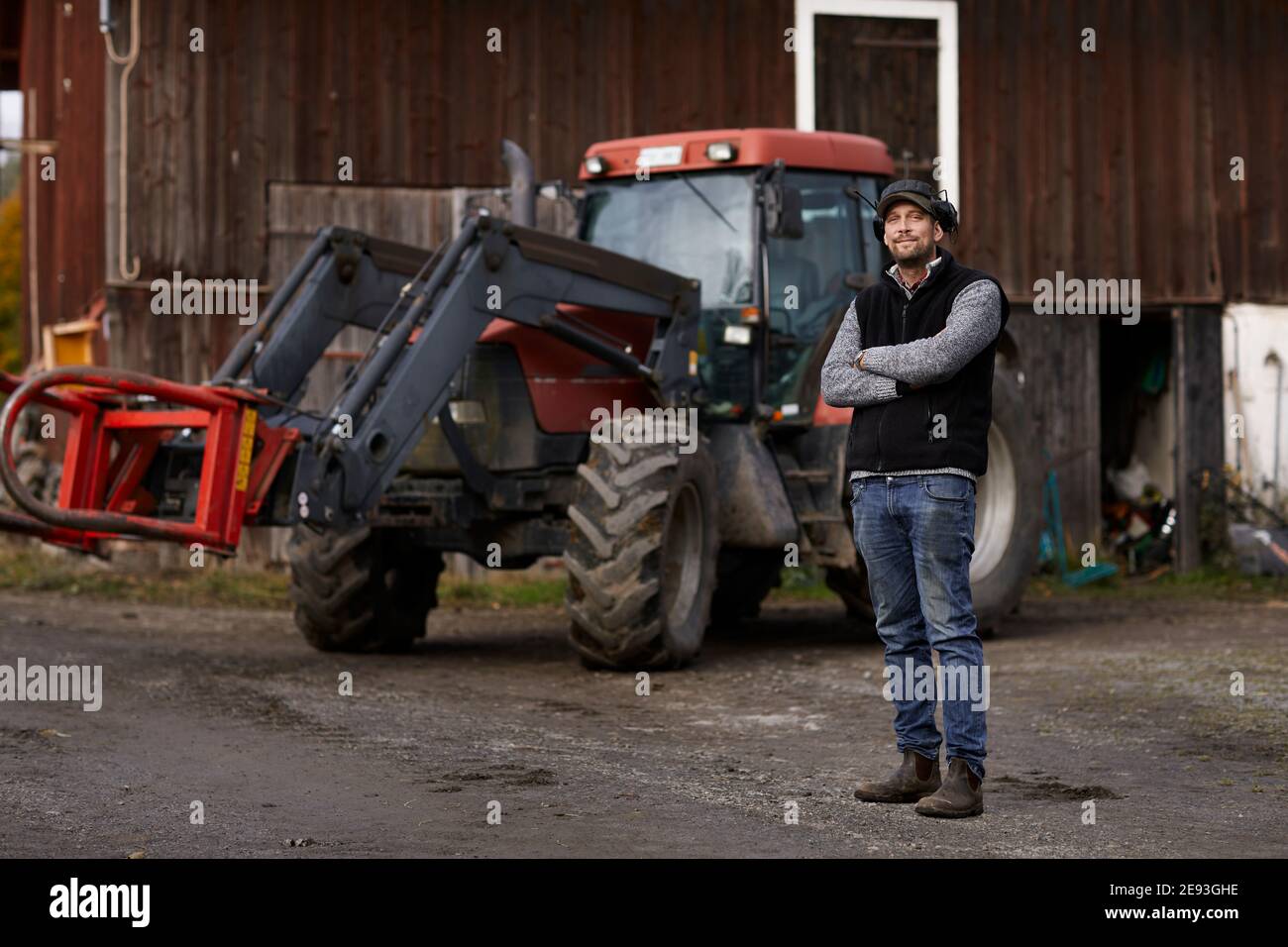 Farmer standing next to tractor Stock Photo - Alamy