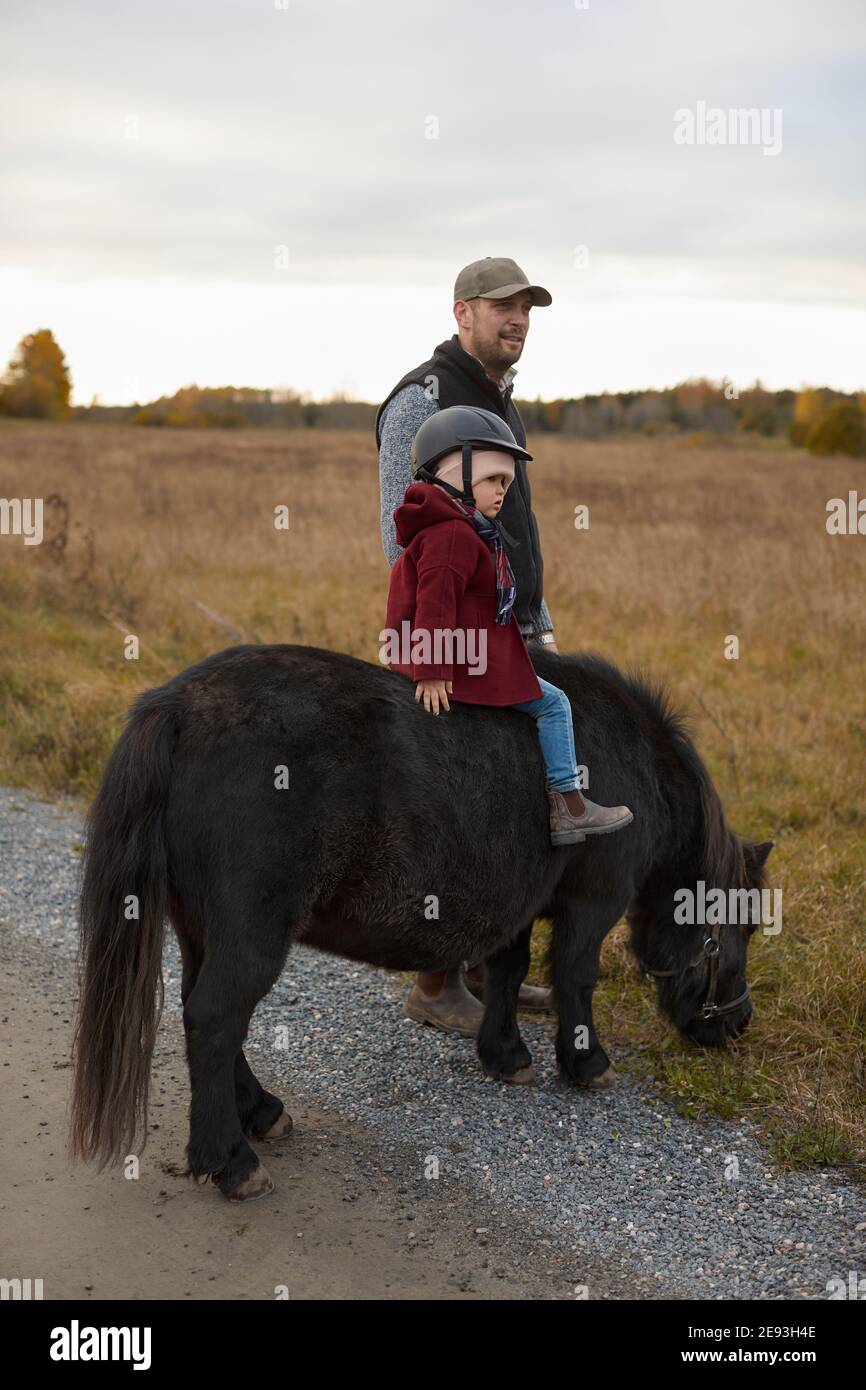 Girls with father riding horse in farm Stock Photo