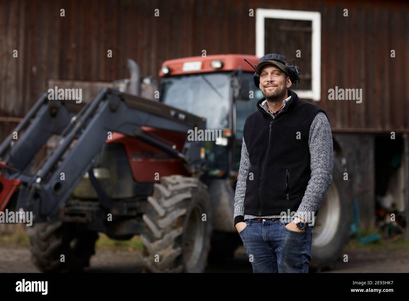 Farmer standing next to tractor Stock Photo - Alamy