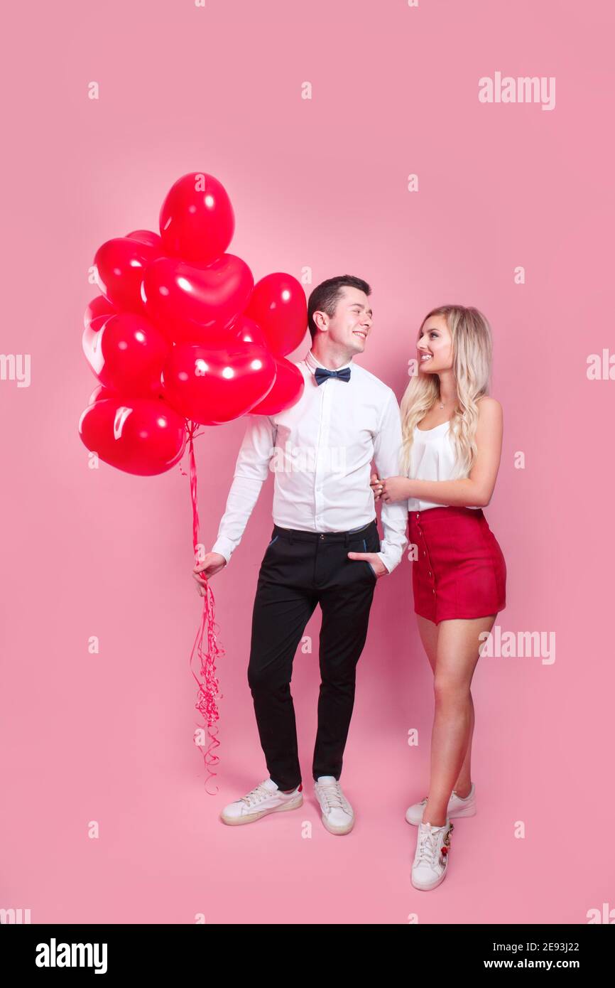 Valentines day. Happy young couple with heart shaped balloons on pink ...