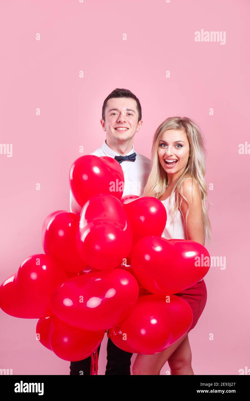 Valentines day. Happy young couple with heart shaped balloons on pink ...