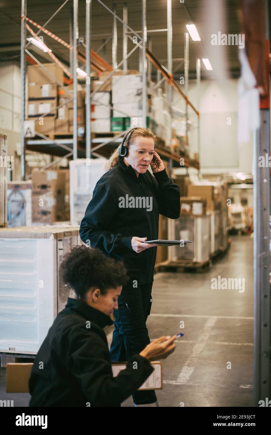 Female manual workers analyzing while holding digital tablet at logistics warehouse Stock Photo