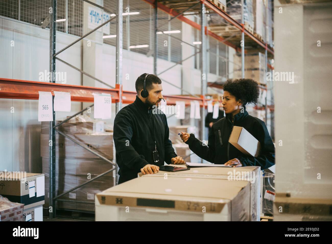 Female entrepreneur planning with male colleague during meeting at warehouse Stock Photo