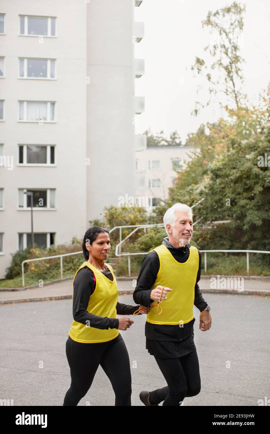 Visually impaired woman jogging with guide runner Stock Photo