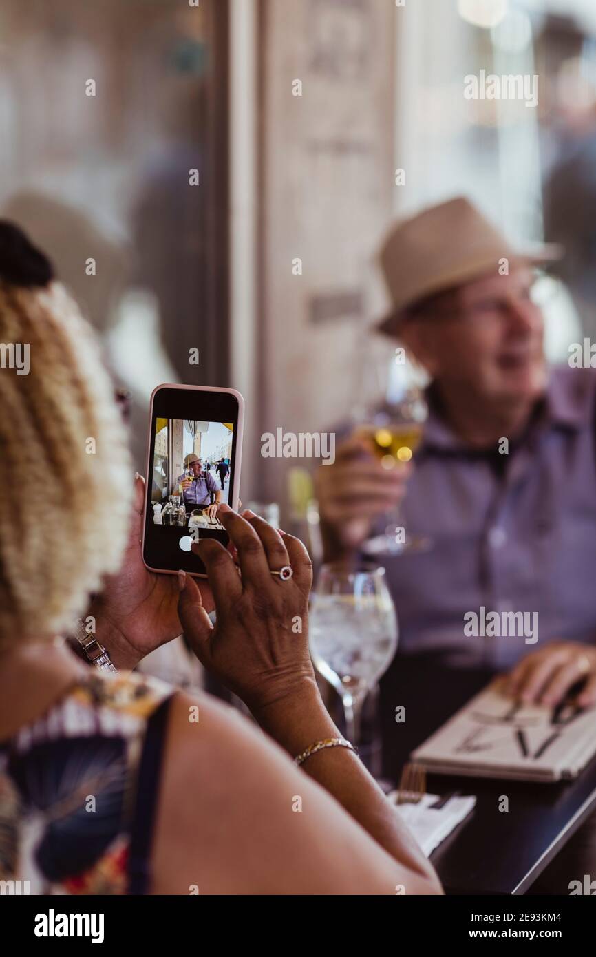 Cropped image of woman photographing man while sitting in cafe Stock Photo