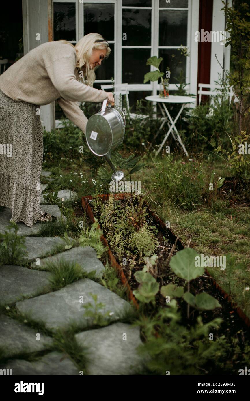Woman watering plants in garden Stock Photo