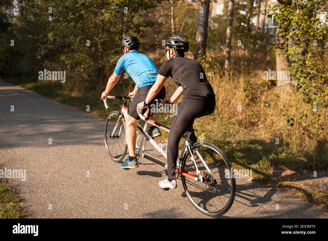 Visually impaired female triathlete training on tandem bicycle with her guide and coach Stock