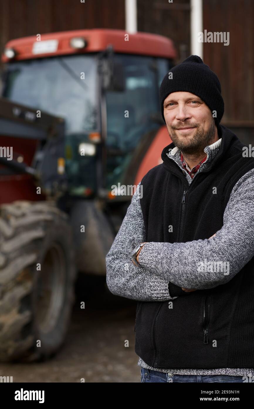 Farmer standing next to tractor Stock Photo - Alamy