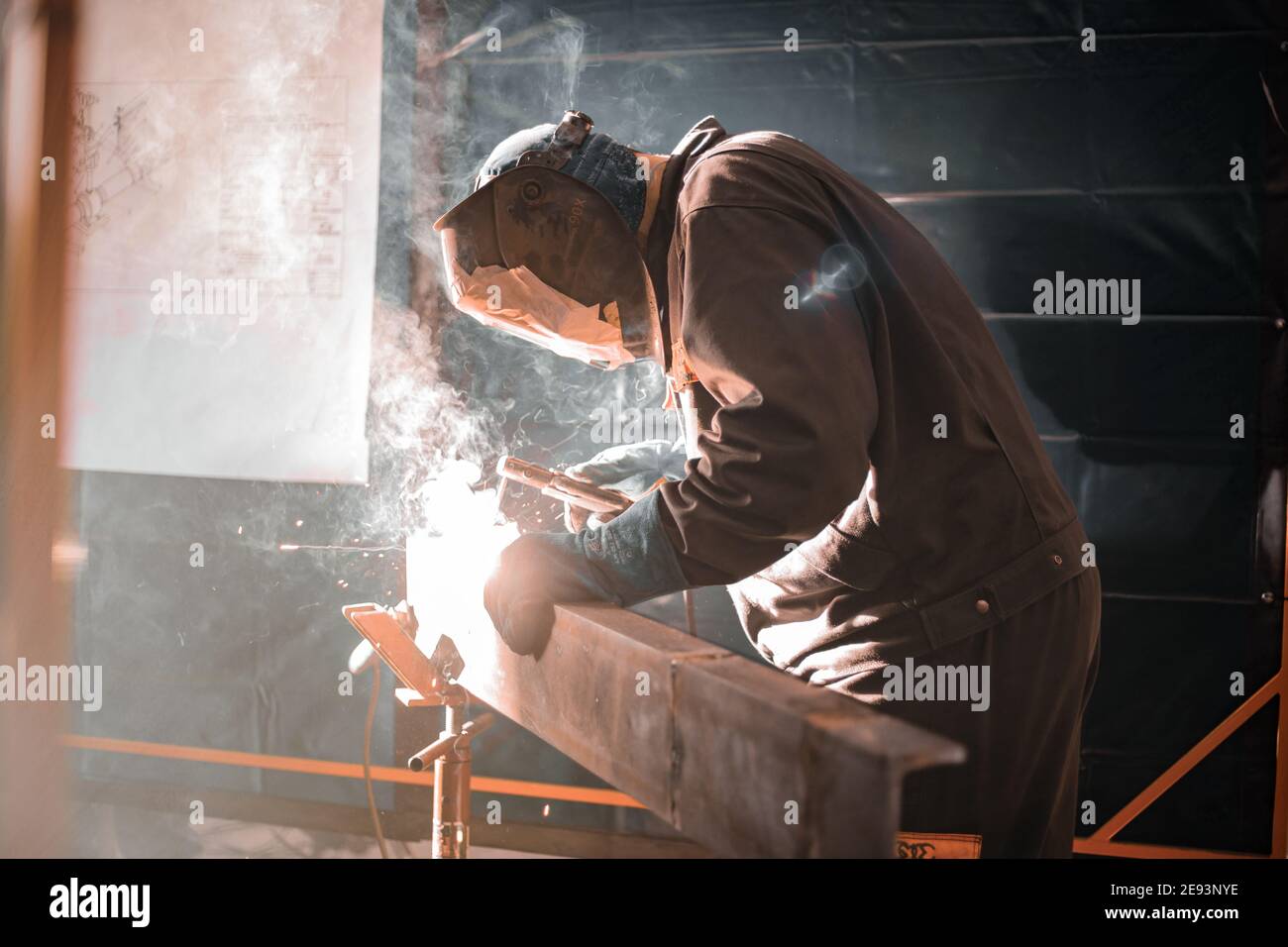 Worker with protective equipment welding metal in the manufacturing