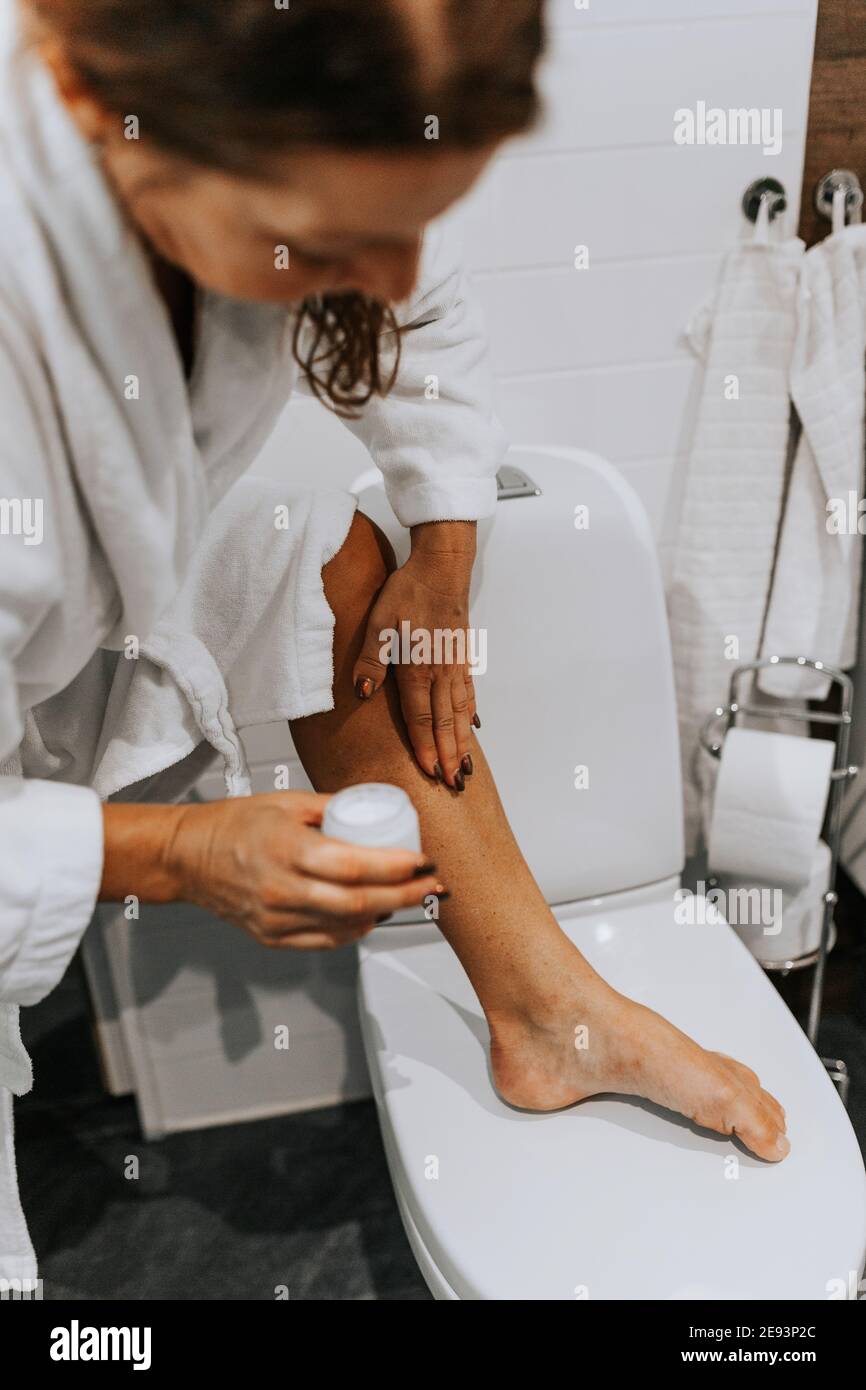 Woman in bathroom applying cream Stock Photo