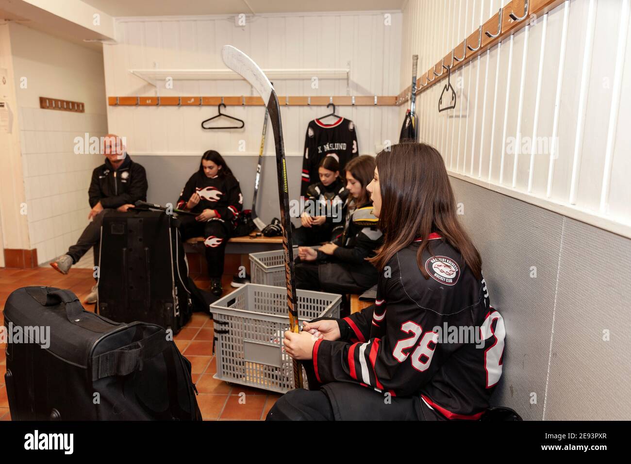 Girl hockey team and coach in locker room Stock Photo