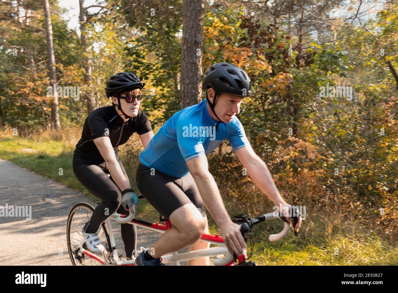 Visually impaired female triathlete training on tandem bicycle with her guide and coach Stock