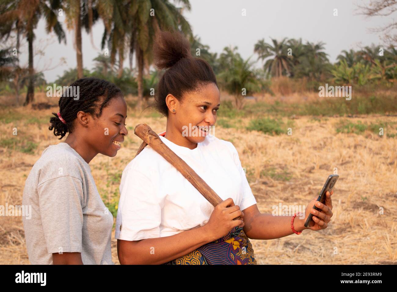 two women viewing a mobile phone at a farmland Stock Photo