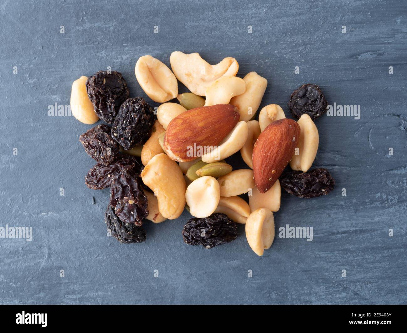 Top view of a portion of nuts and dried fruit on a blue painted wood background. Stock Photo