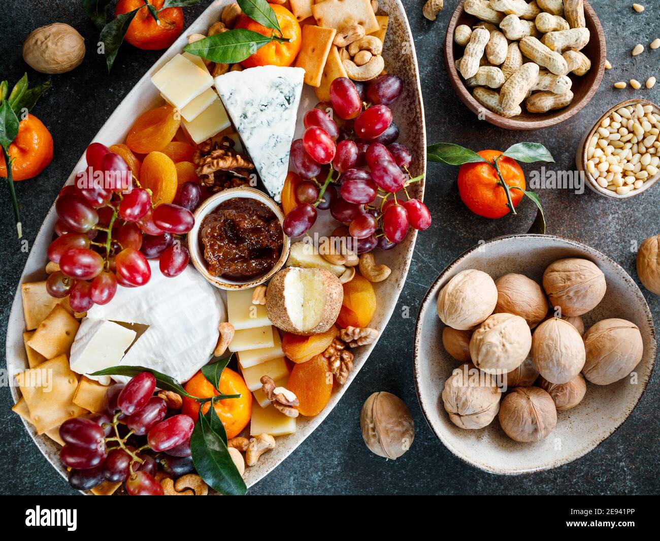 Big cheese board with appetizer assortment. Grape, cheese, nuts, jam and bread. Stock Photo