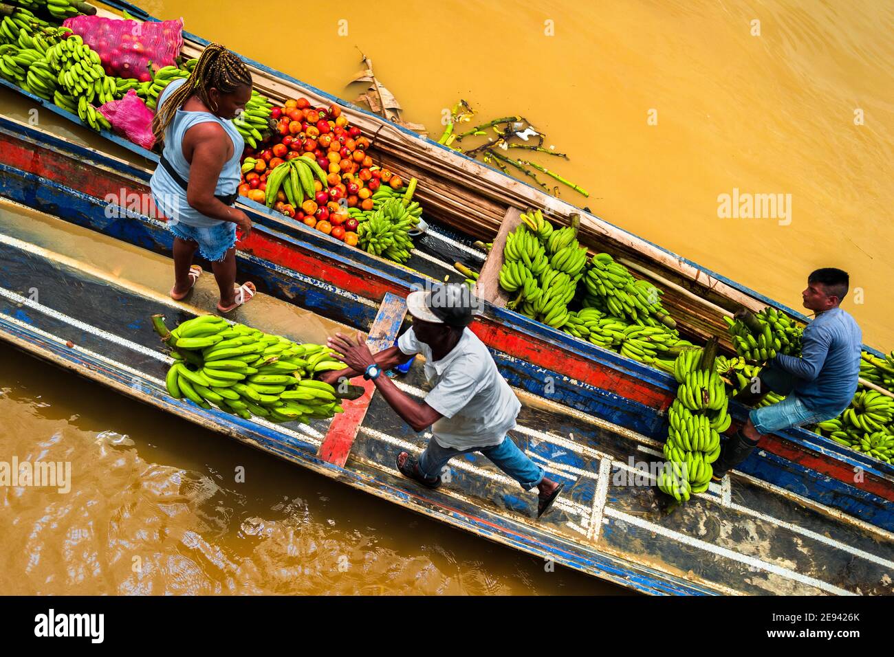 Afro-Colombian workers unload bunches of bananas from cargo boats in the Atrato river market in Quibdó, Chocó, the Pacific region of Colombia. Stock Photo