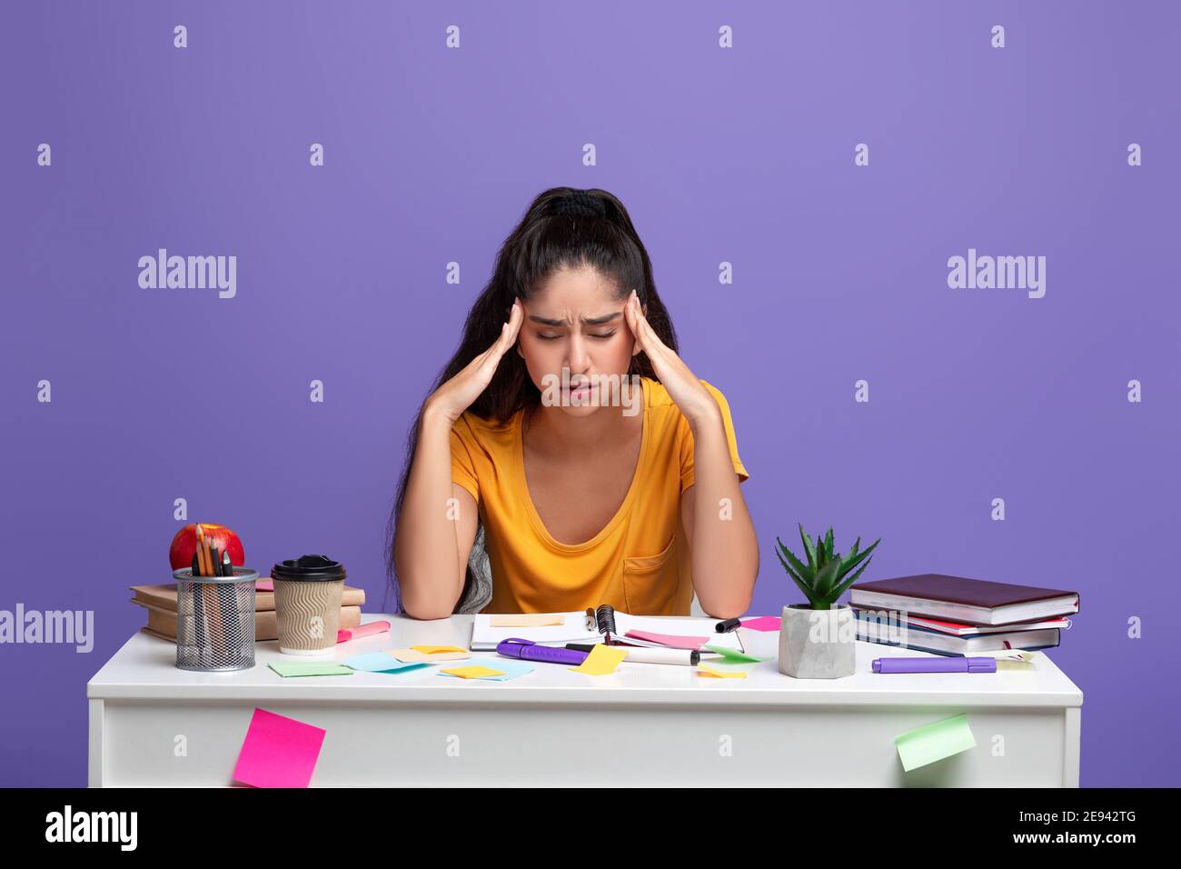 Tired indian woman sitting at desk massaging her temples Stock Photo ...