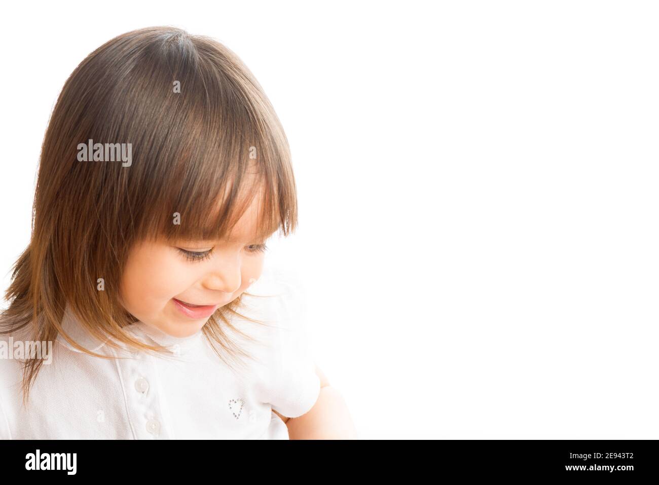 Two years old girl smiling looking down. Stock Photo