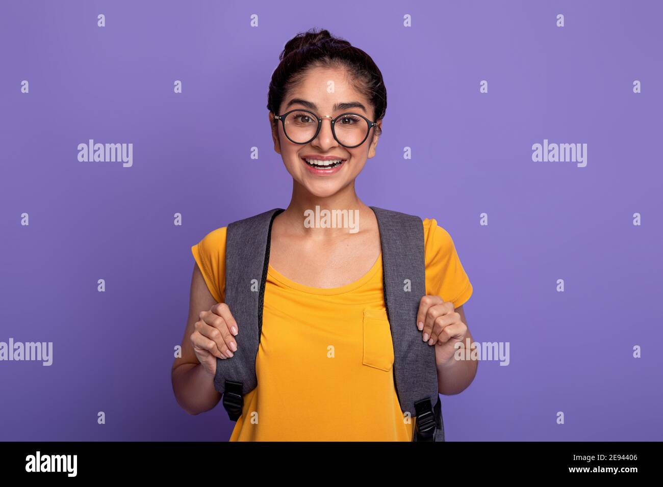 Happy indian female student wearing backpack and eyeglasses Stock Photo