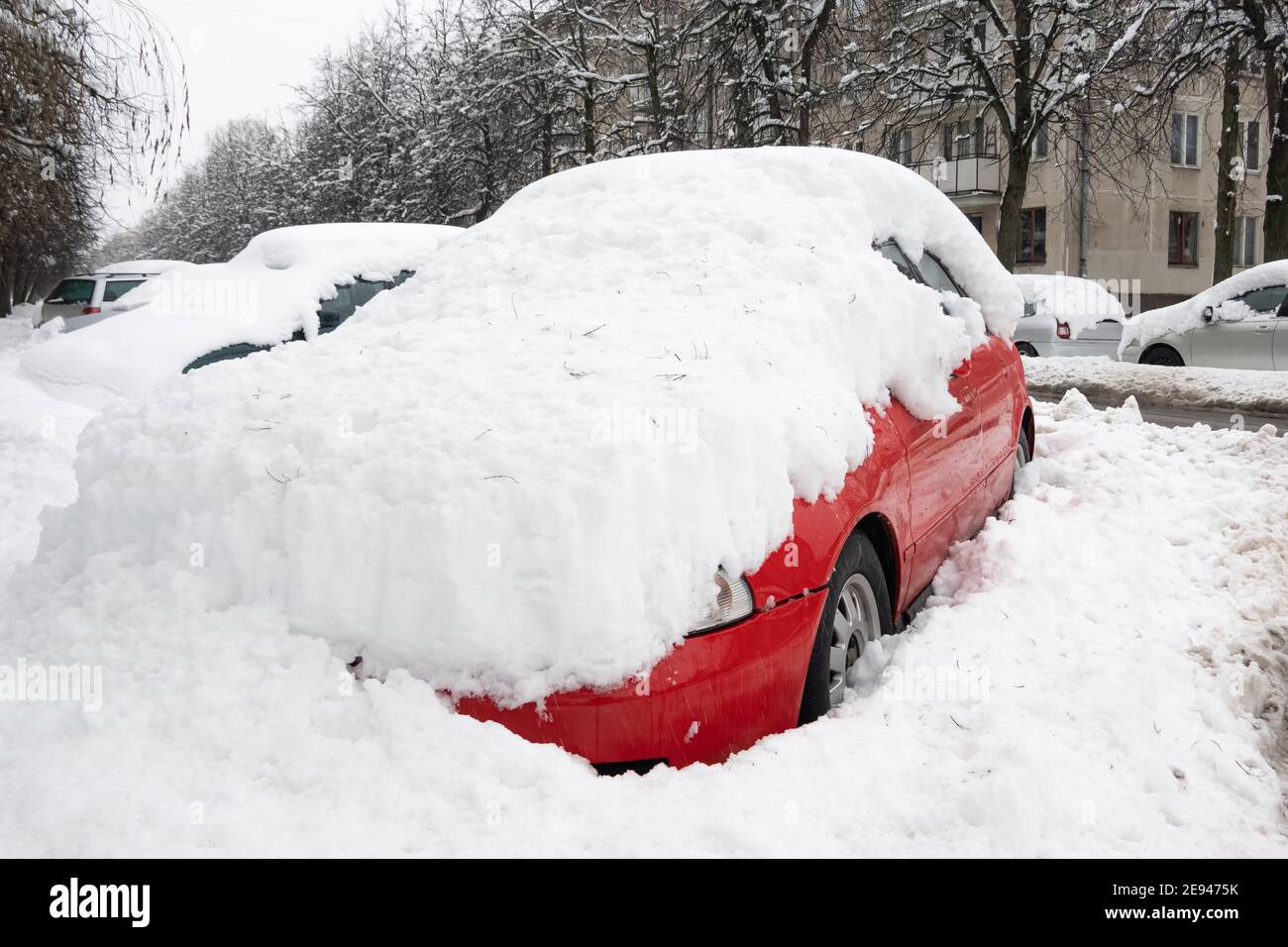 Car under thick blanket of snow after storm. Vehicles buried under ice