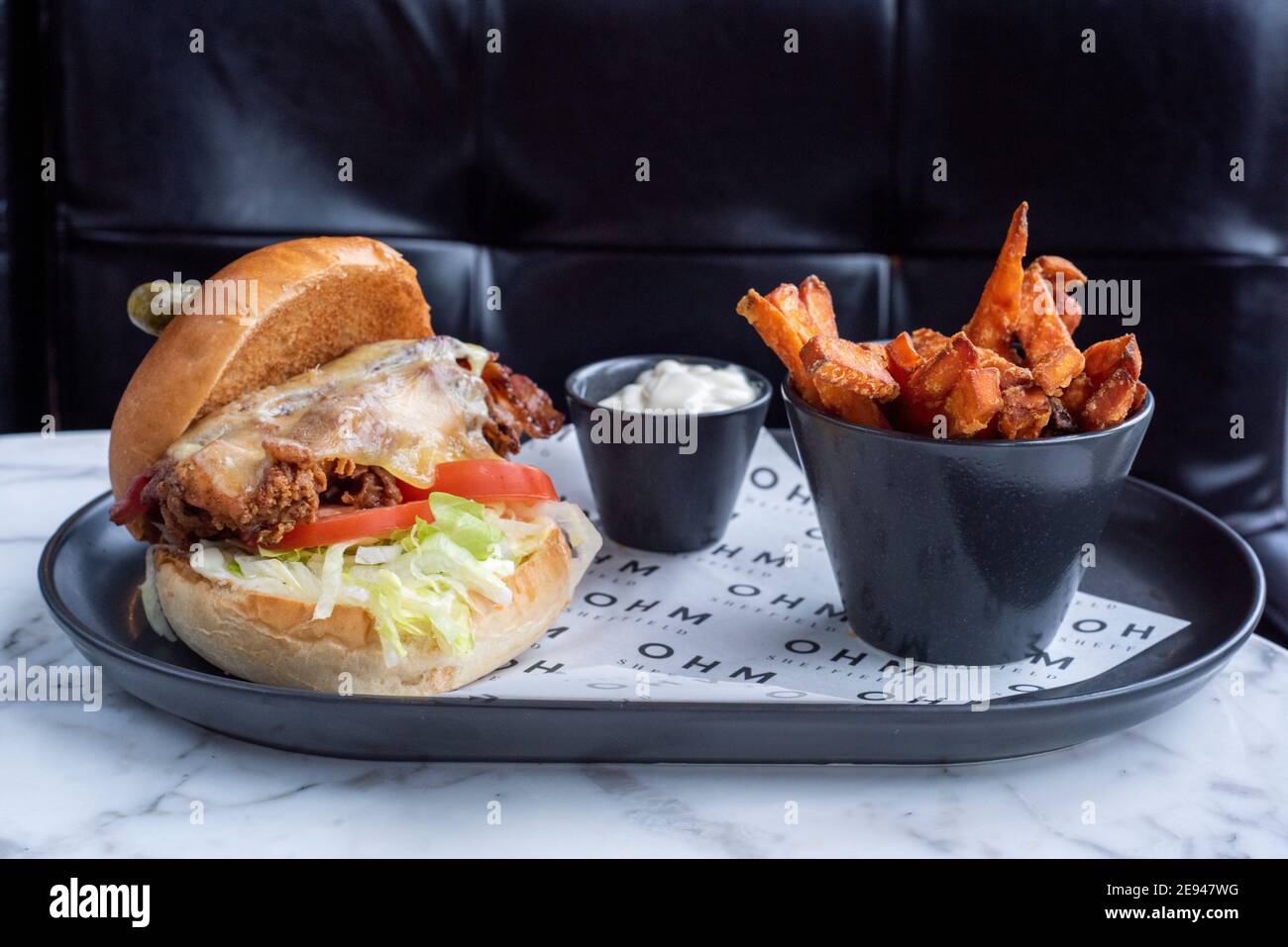 Sheffield, UK - 03 Aug 2017: Chicken cheese and bacon burger served with sweet potato fries at OHM, Fitzwilliam Street Stock Photo
