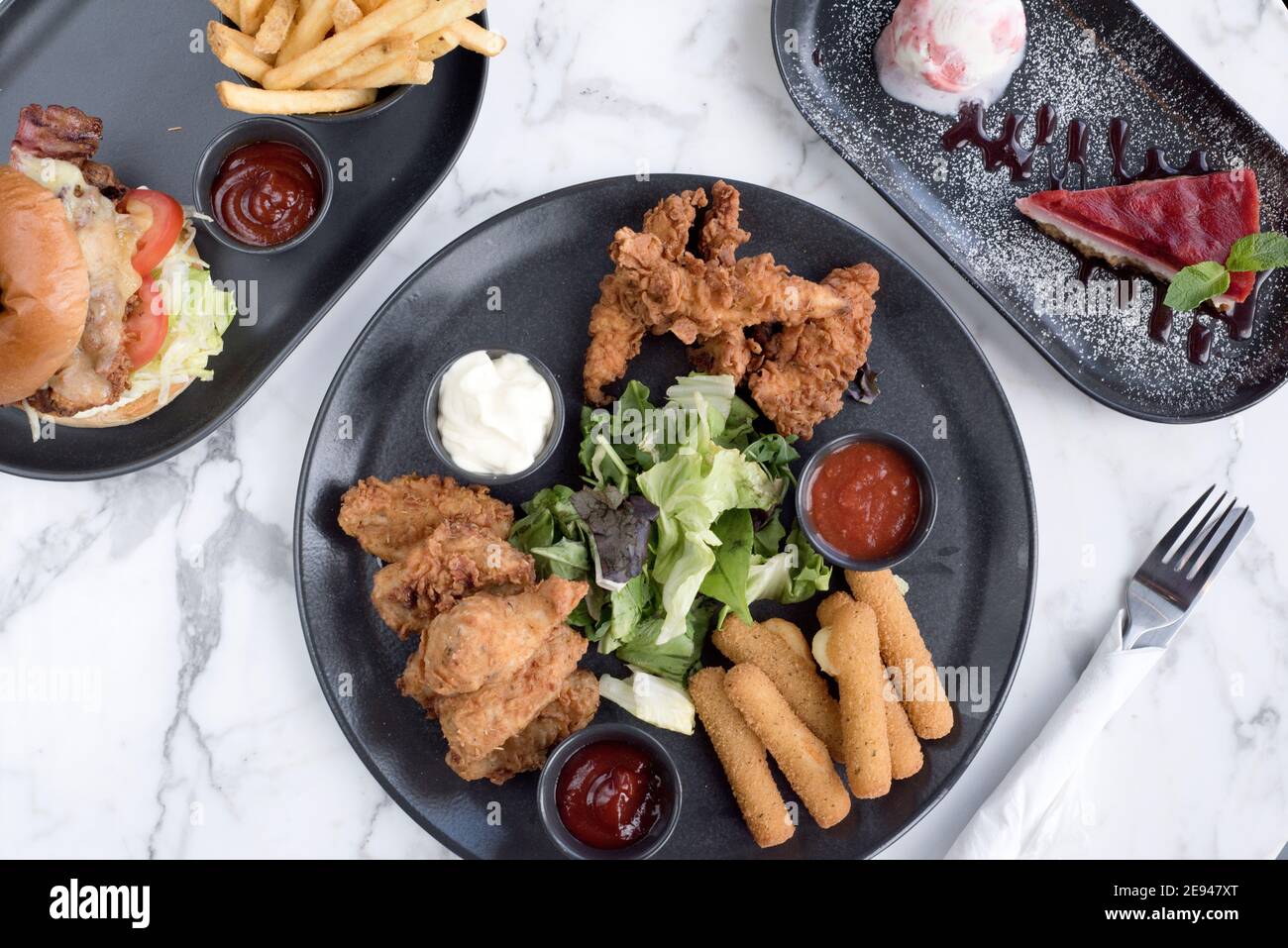 Sheffield, UK - 03 Aug 2017: Southern fried chicken, mozarrella sicks share platter, cheeseburger and fries and cheesecake at OHM, Fitzwilliam Street Stock Photo