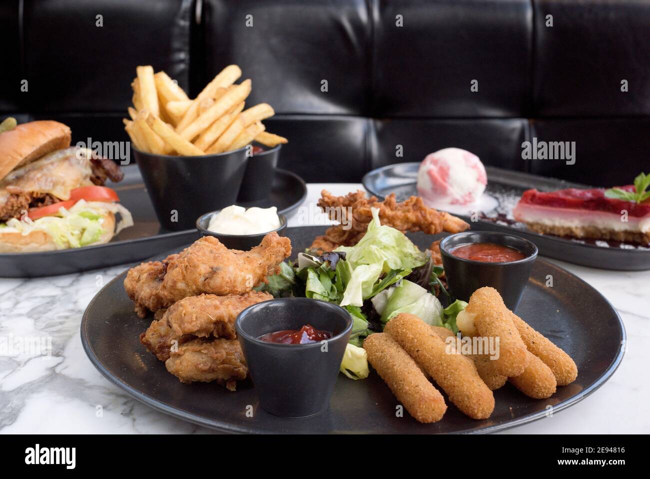 Sheffield, UK - 03 Aug 2017: Southern fried chicken, mozzarella sticks share platter, cheeseburger and fries and cheesecake at OHM, Fitzwilliam Street Stock Photo