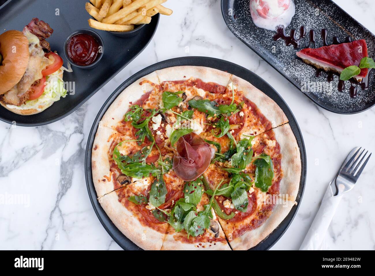 Sheffield, UK - 03 Aug 2017: pepperoni salami and rocket pizza, cheeseburger and fries and cheesecake at OHM, Fitzwilliam Street Stock Photo