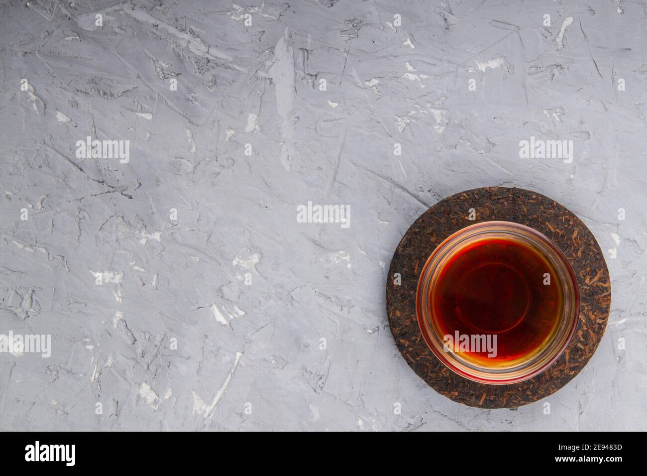 Pu erh tea cake and chinese tea cup on plaster background with place for text Stock Photo