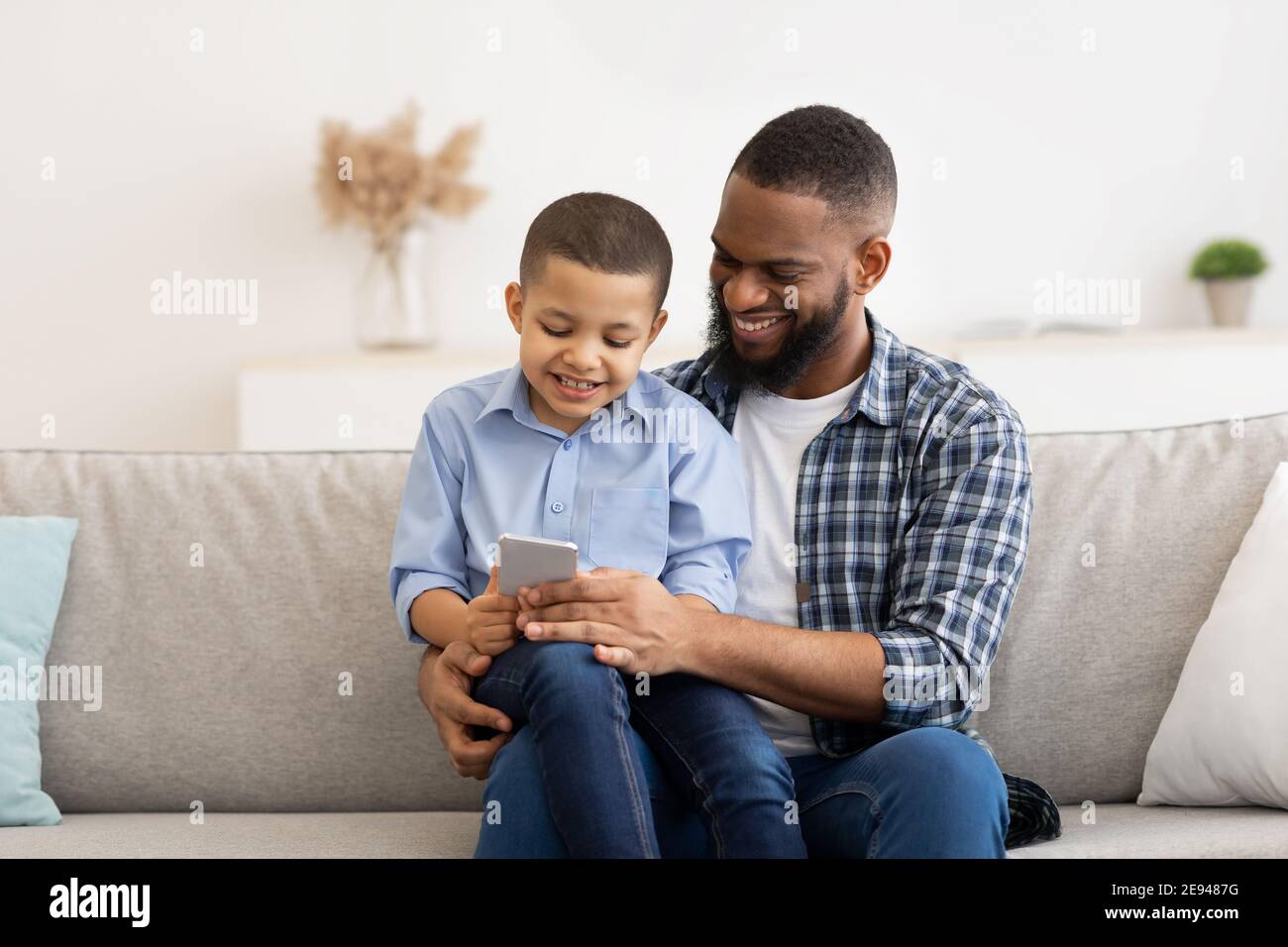 Little African Boy And His Dad Using Smartphone At Home Stock Photo - Alamy