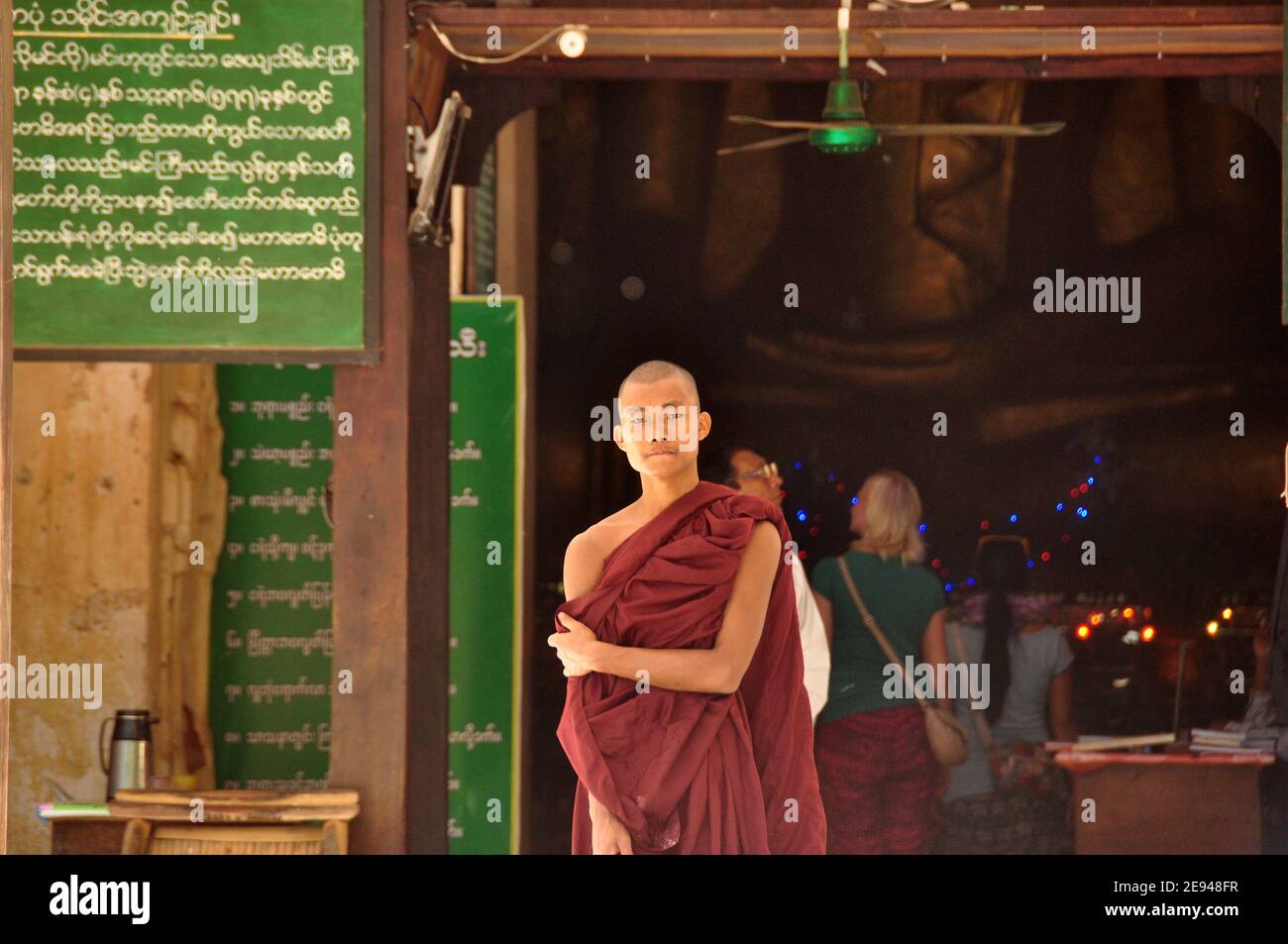 BAGAN, MYANMAR - NOV 13, 2015: Ethnic monk portrait. Young Asian man in robe of monk standing in front of temple entrance. Mingalazedi pagoda. Sulaman Stock Photo