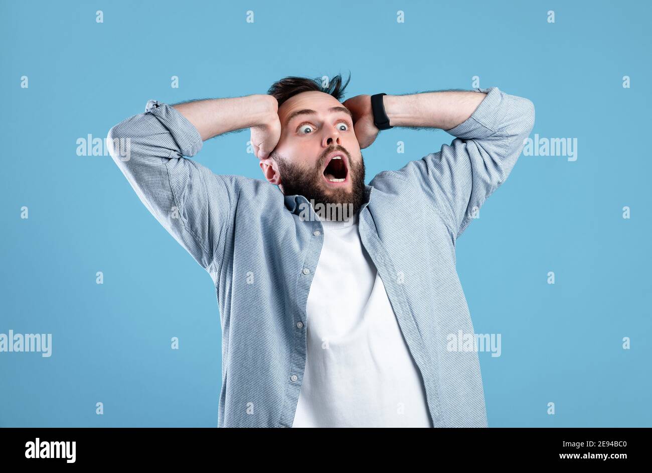 Shocking offer. Extremely surprised young guy shouting OMG in disbelief on blue studio background Stock Photo