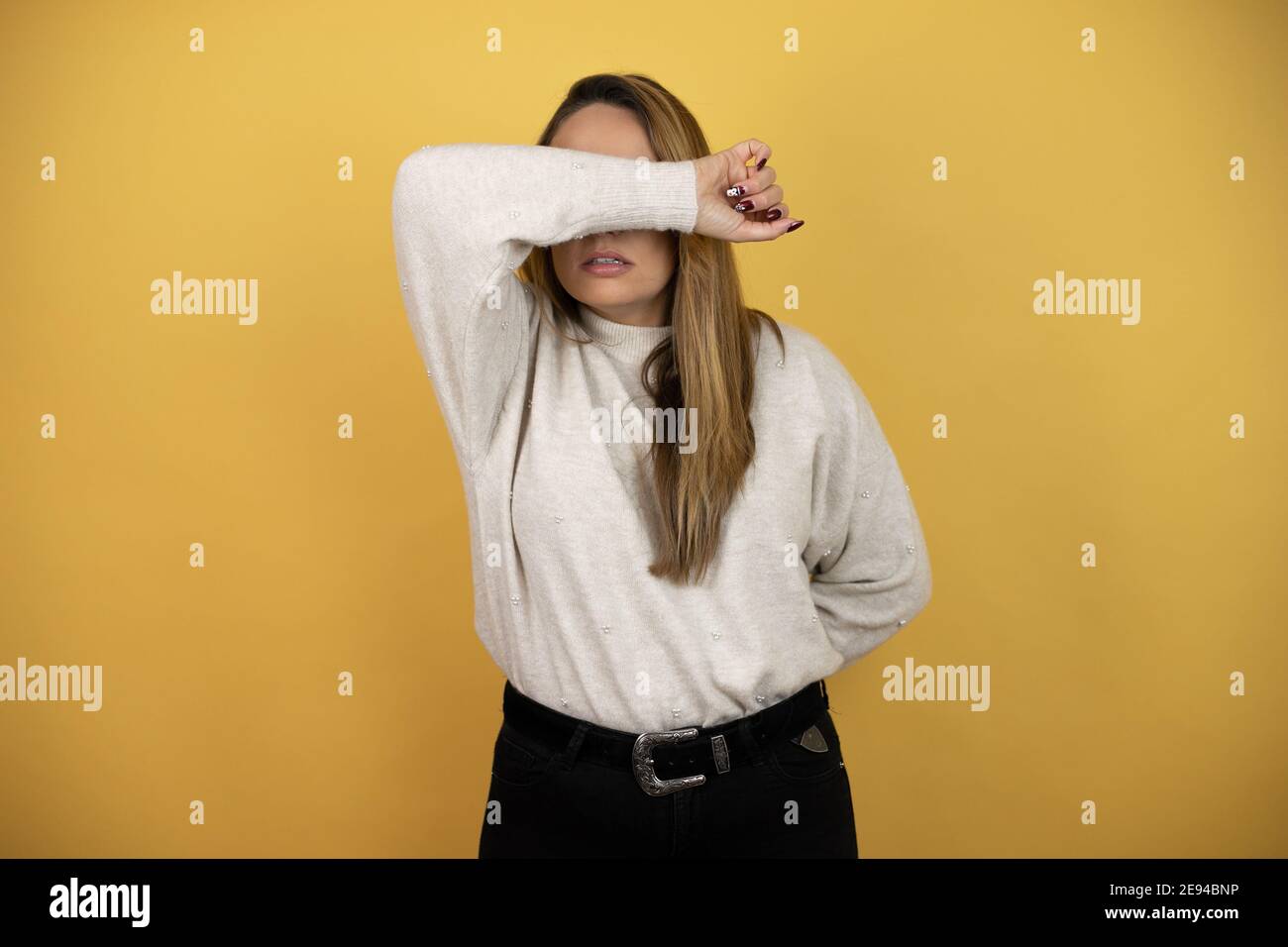 Pretty woman with long hair covering eyes with arm smiling cheerful and