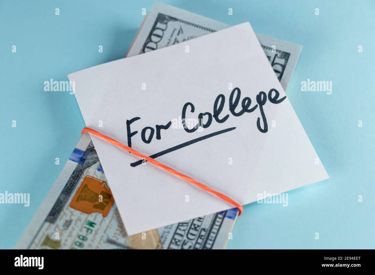 Dollars cash money in rubber band with text written note FOR COLLEGE , on copy space background - concept of financial planning to save money for purp Stock Photo