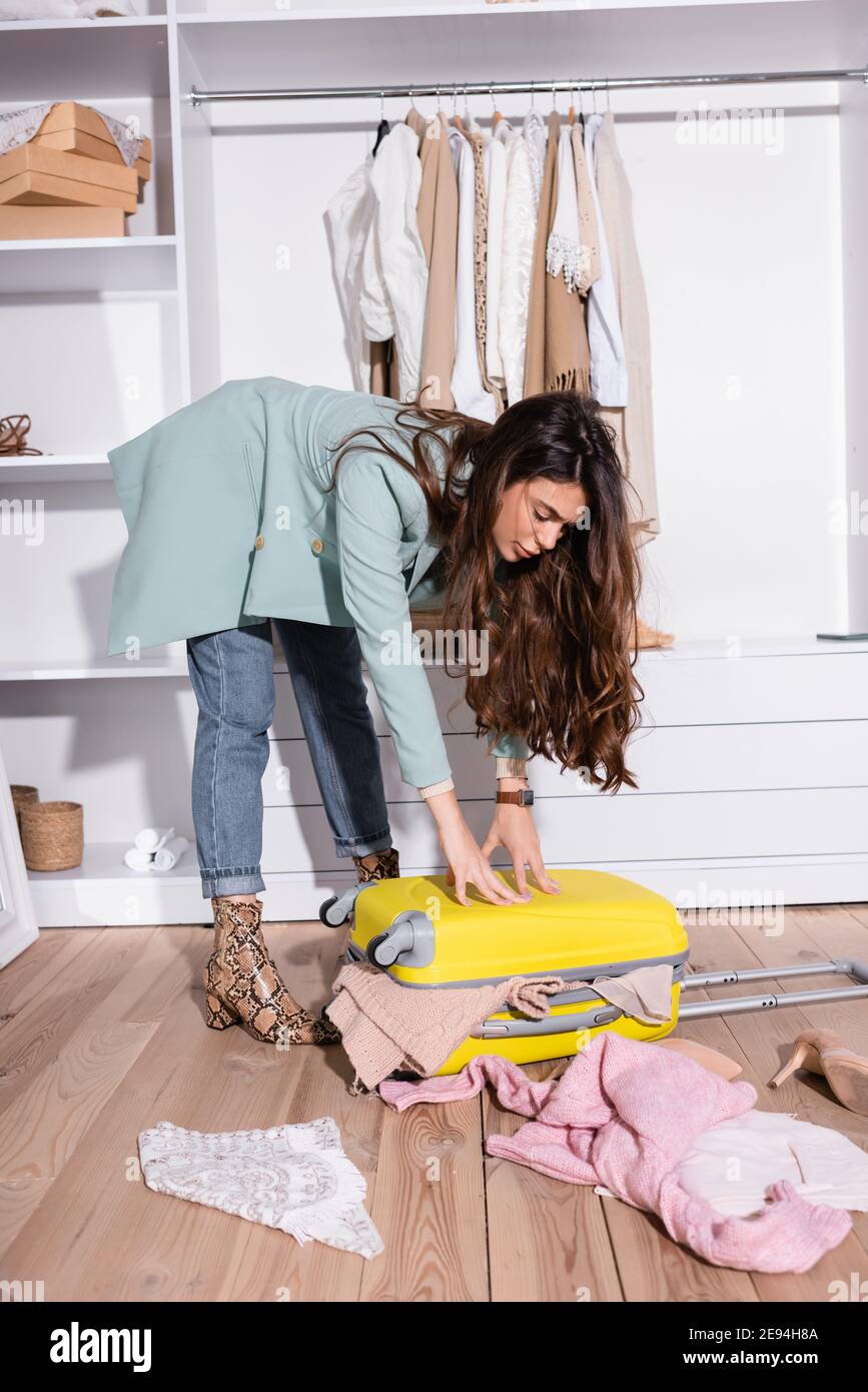 Young woman pressing suitcase with clothes in wardrobe Stock Photo Alamy