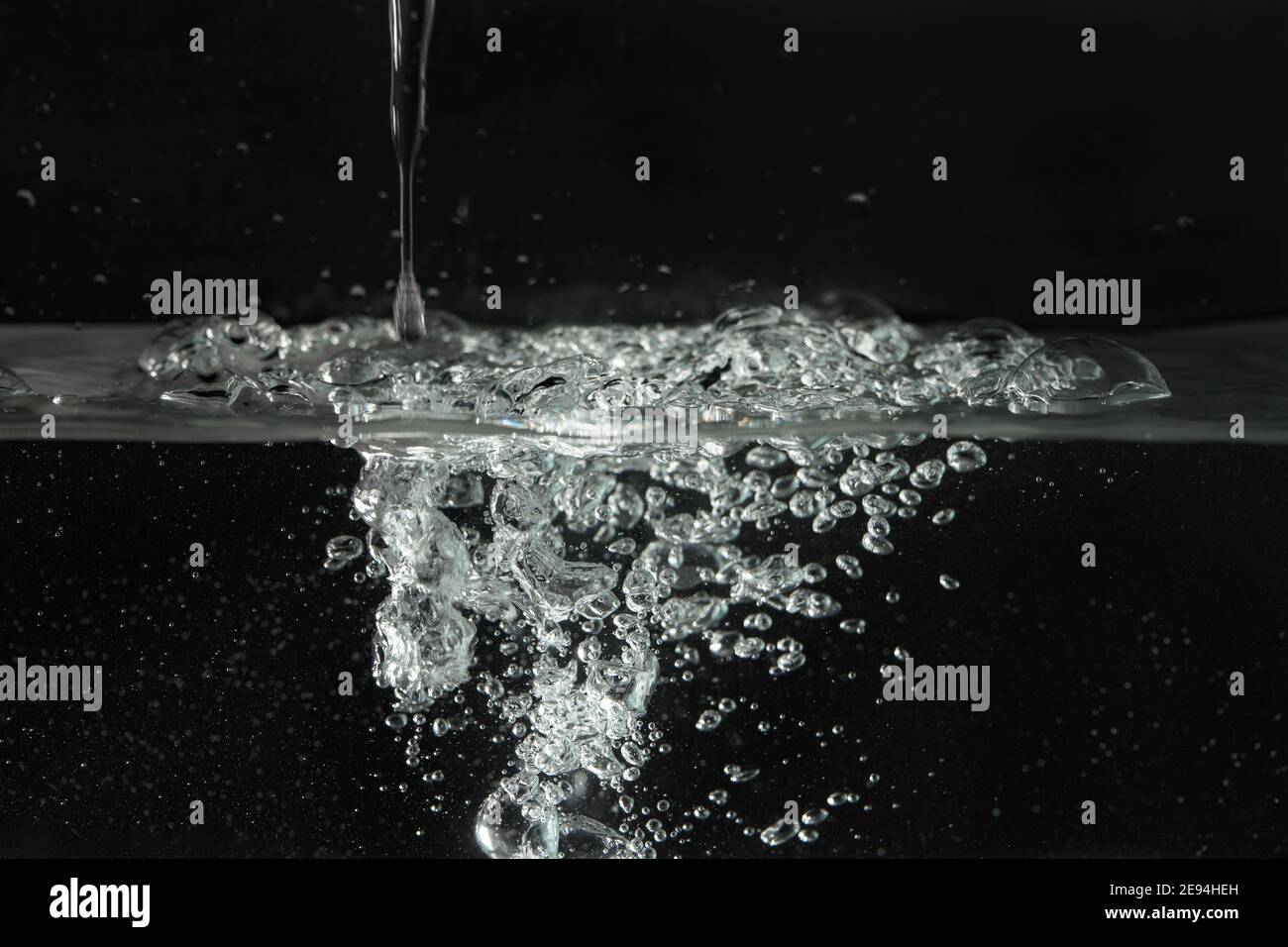 Water splashing as it's poured into aquarium tank, black background