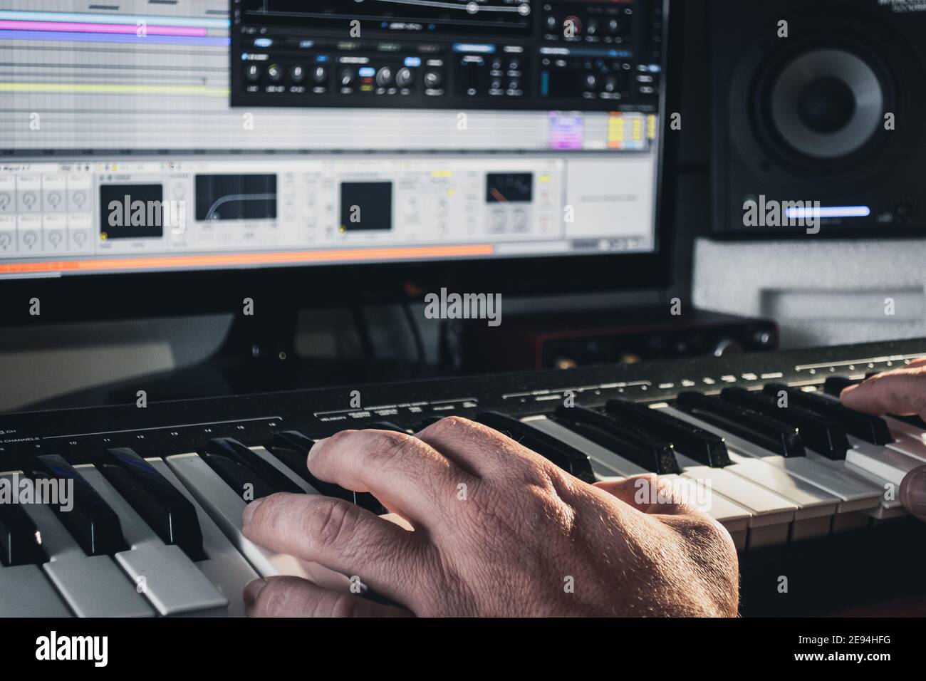 Music producer working with a midi keyboard synthesizer and a computer